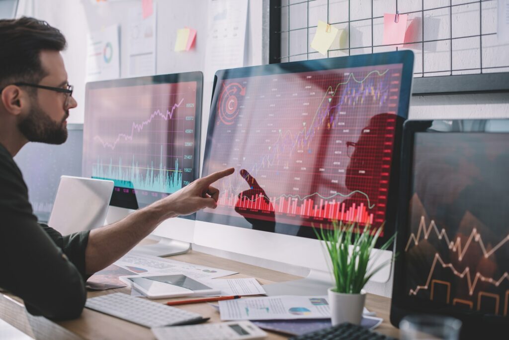 Side view of data analyst pointing with finger at charts on computer monitor while testing